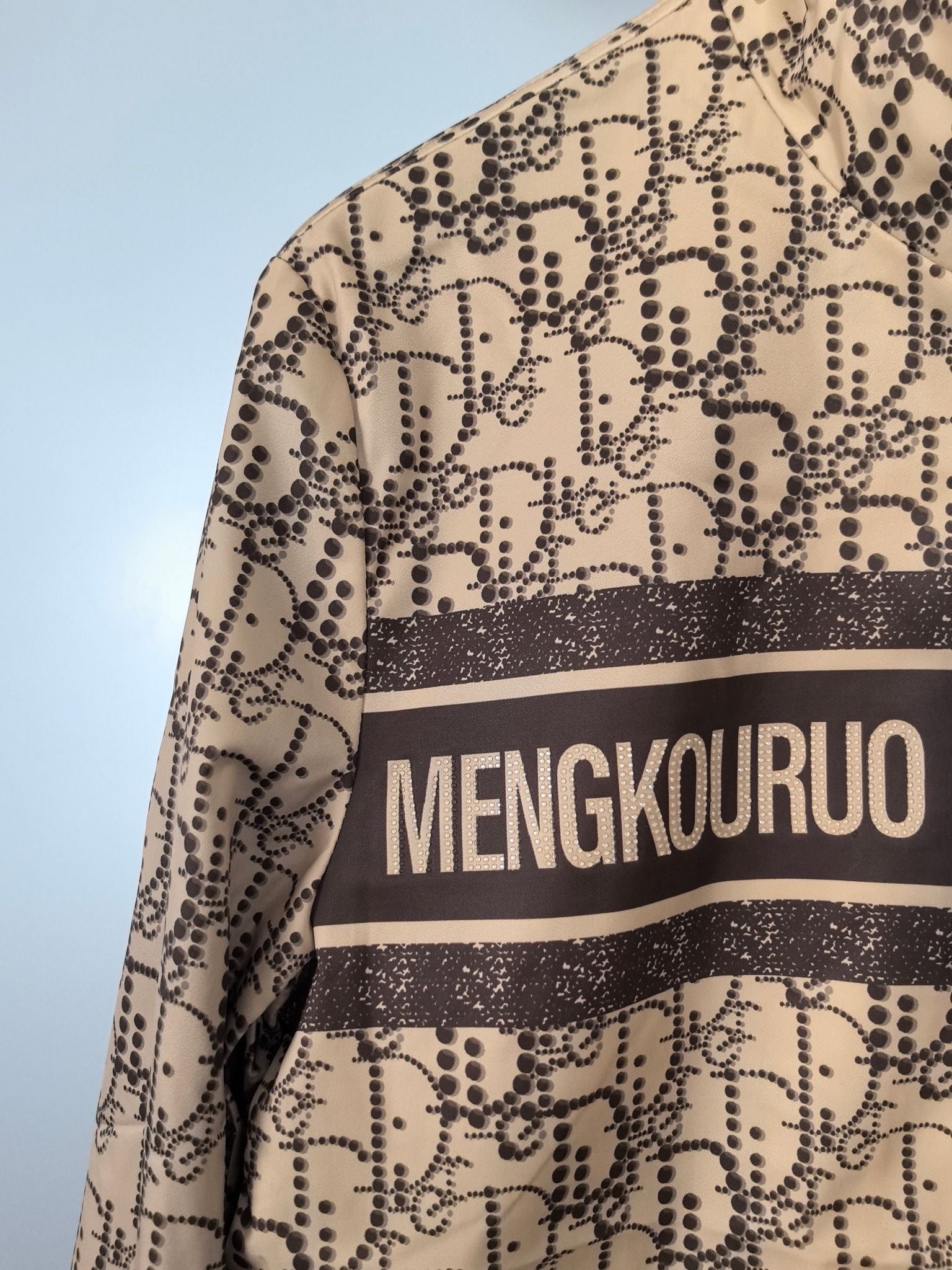 Beige patterned long jacket with MENGKOUROU stripe across upper front, close-up