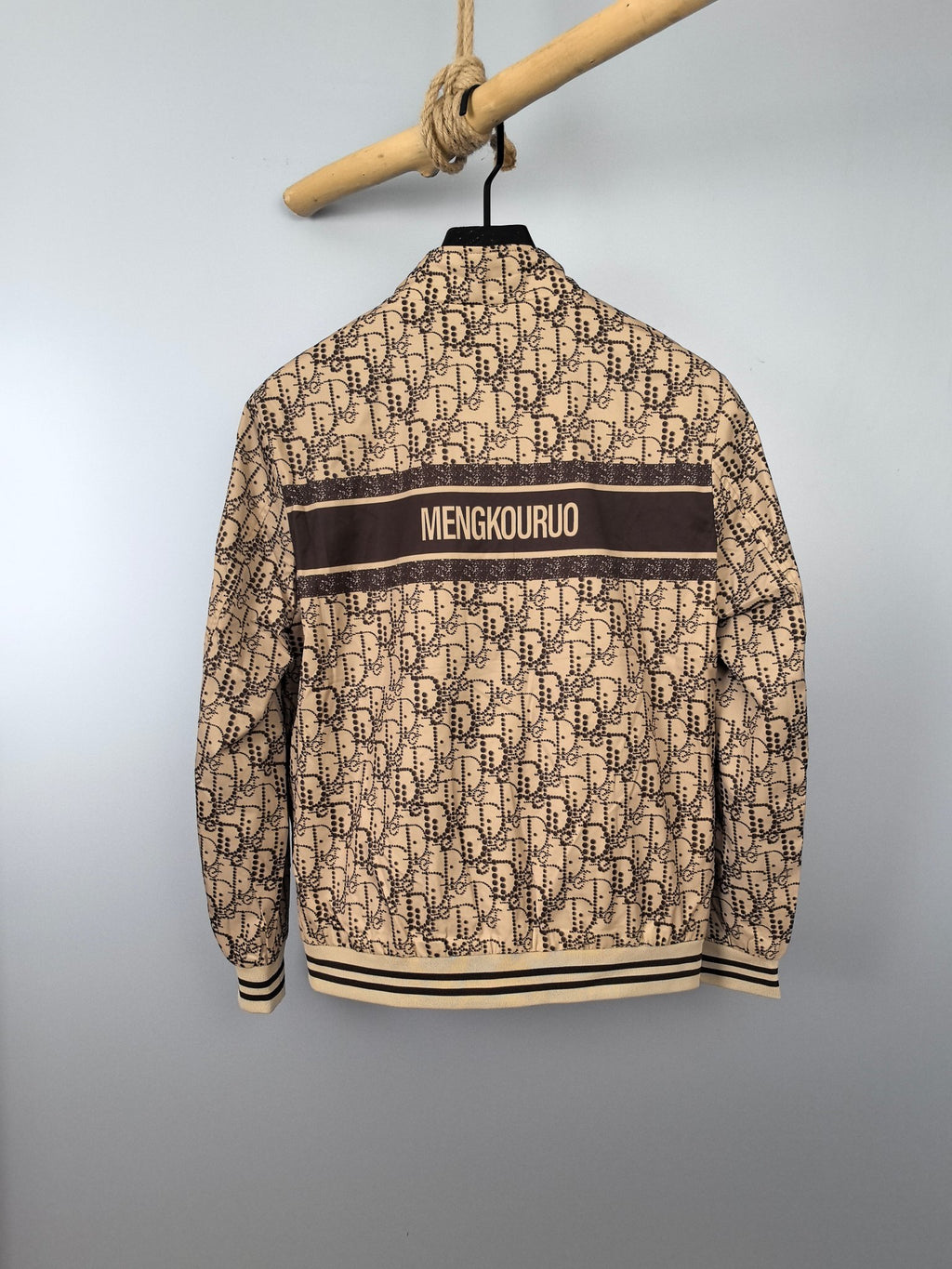 Beige long zip jacket with dark back stripe and ribbed hem, hanging on hanger