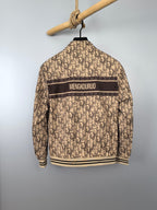 Beige long zip jacket with dark back stripe and ribbed hem, hanging on hanger