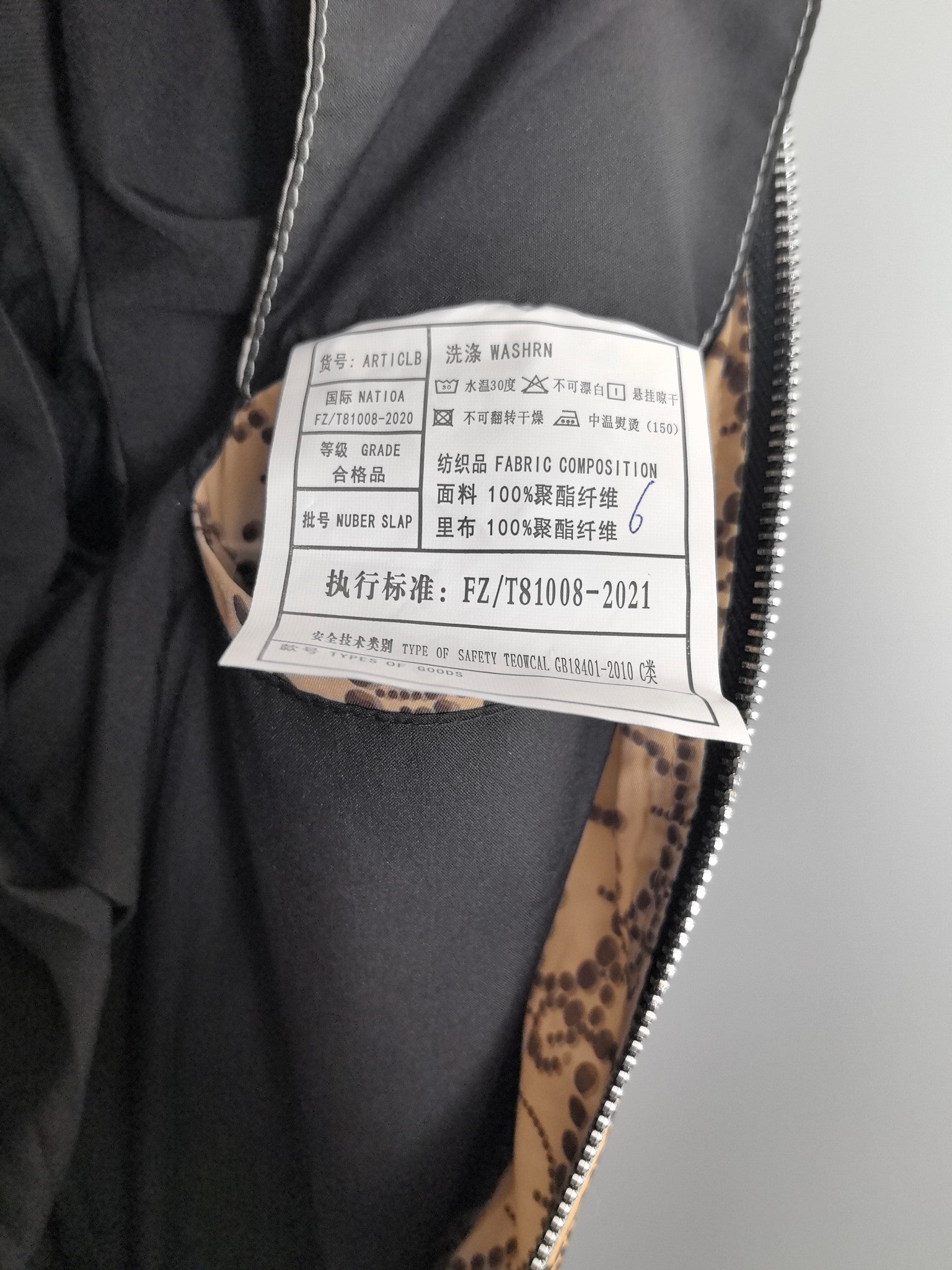 Black and patterned long jacket with white care tag showing washing instructions