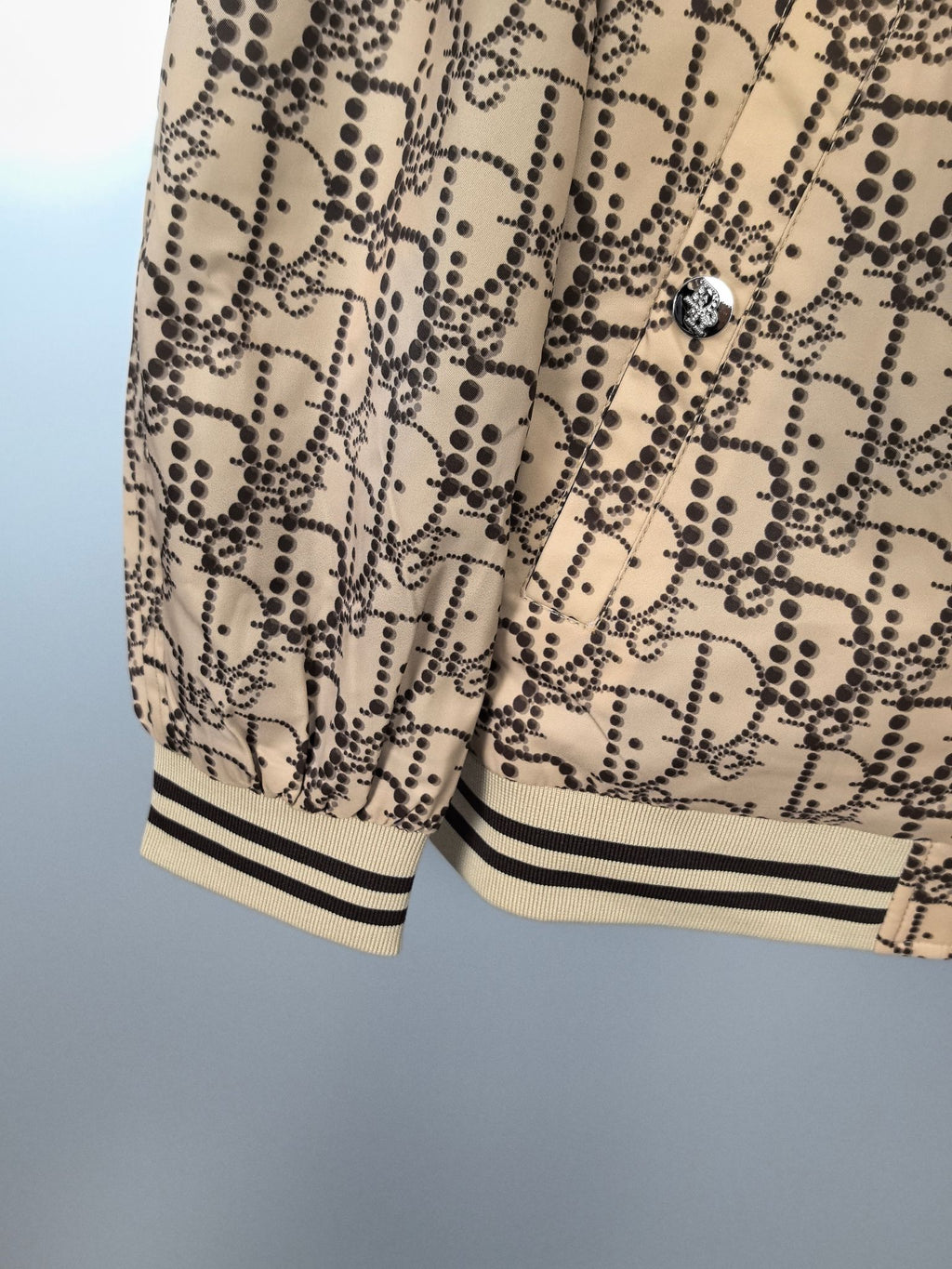 Beige patterned long jacket with ribbed cuffs and hem, partial view