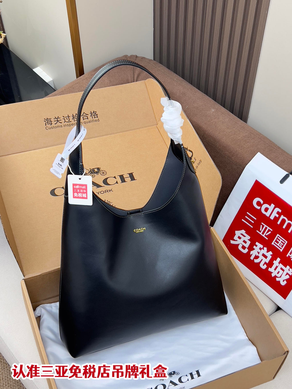 Dark blue shoulder bag with top handle, hobo shape, and gold logo on front