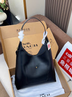 Dark blue hobo shoulder bag with curved top handle and hanging retail tag