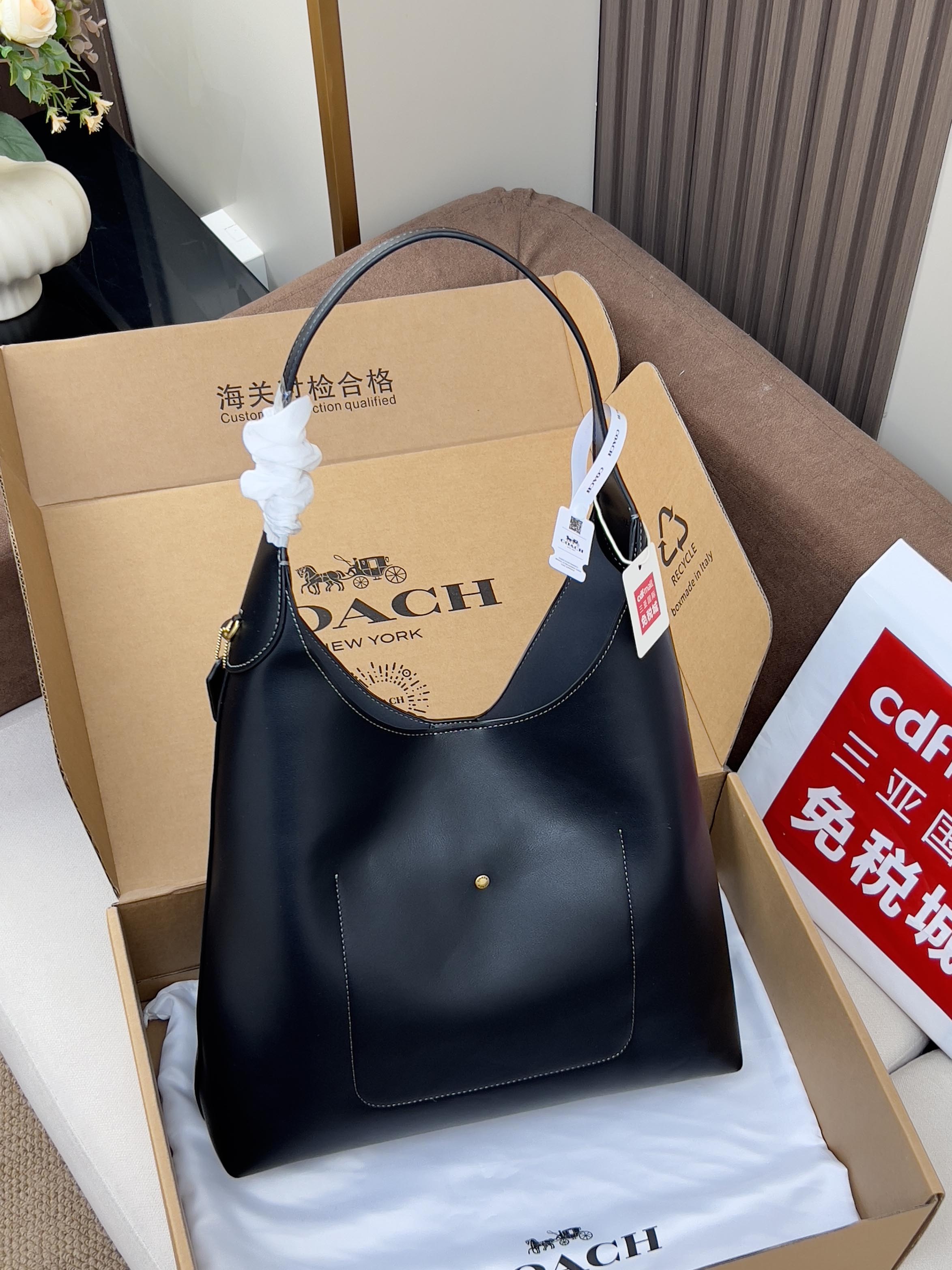 Dark blue hobo shoulder bag with curved top handle and hanging retail tag