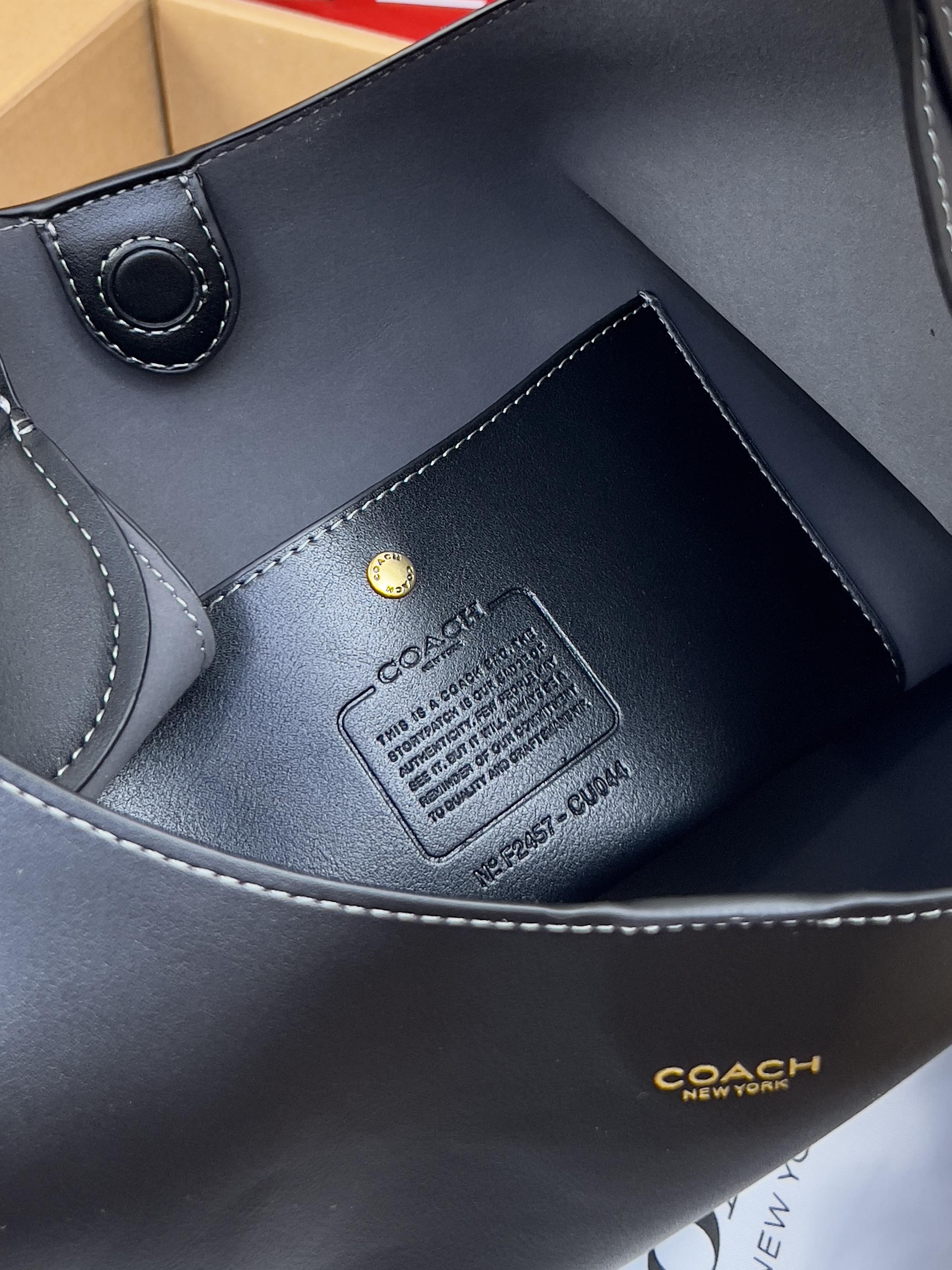 Dark blue leather bag interior corner with stitched trim and logo label patch