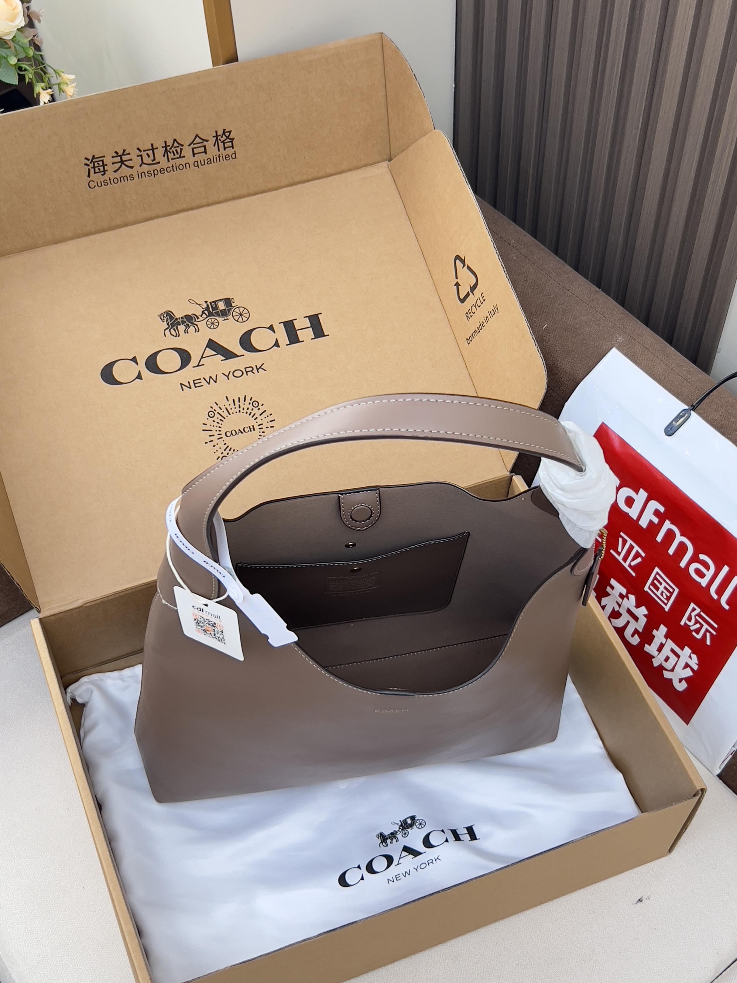 Taupe leather handbag with open top and interior lining, in its gift box.
