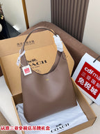 Taupe leather handbag with top handles, displayed in a gift box.