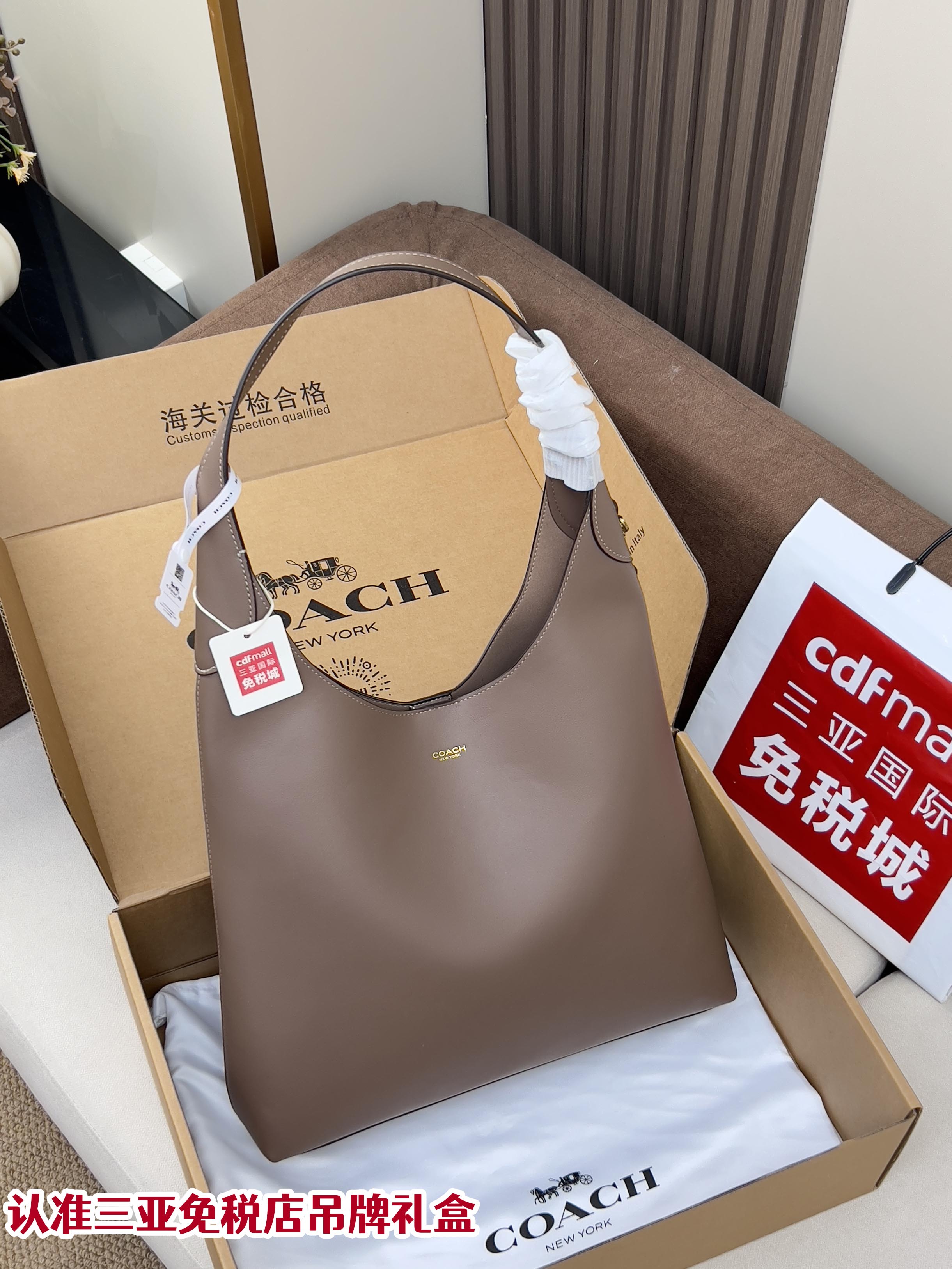 Taupe leather handbag with top handles, displayed in a gift box.
