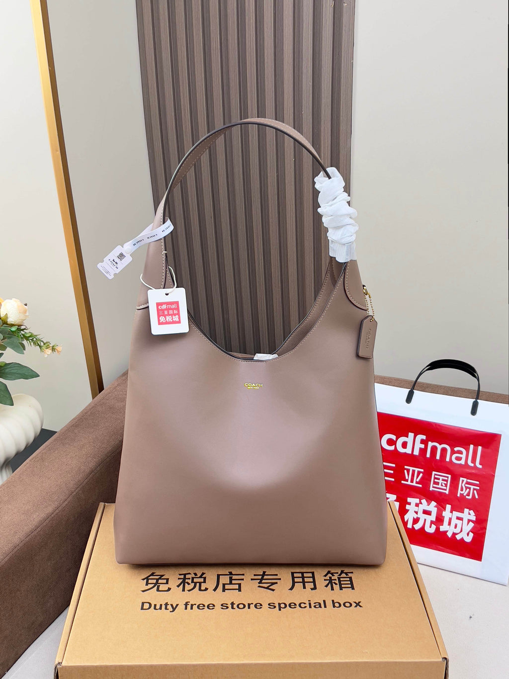 Taupe leather handbag with top handles, shown upright with price tag.