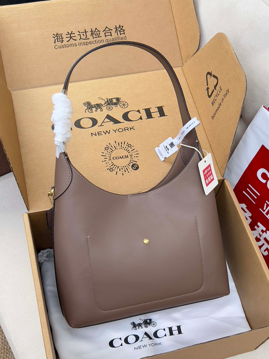 Taupe COACH handbag with curved top handles and small front logo detail