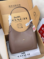 Taupe COACH handbag with curved top handles and small front logo detail