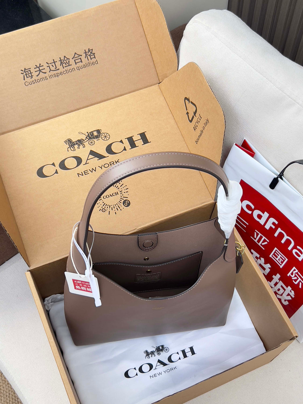 Taupe COACH handbag with curved top handles and hanging tag