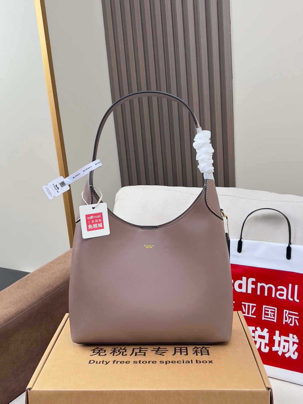 Taupe COACH handbag with curved top handles and front logo detail