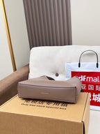 Taupe handbag and retail box on sofa