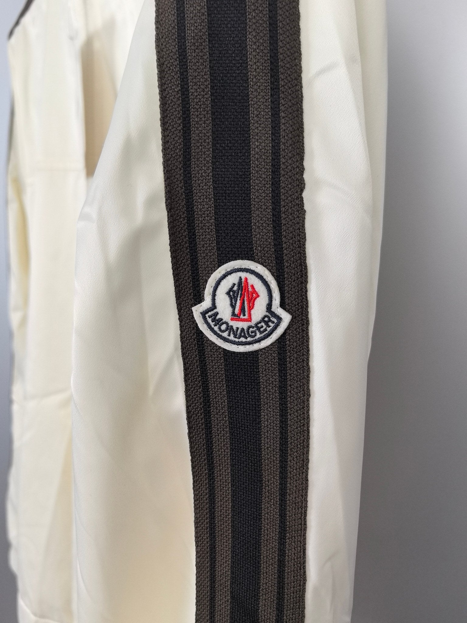 Moncler off-white jacket sleeve with black striped band and round logo patch