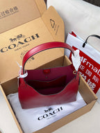Red leather tote-style bag with top handles in gift packaging