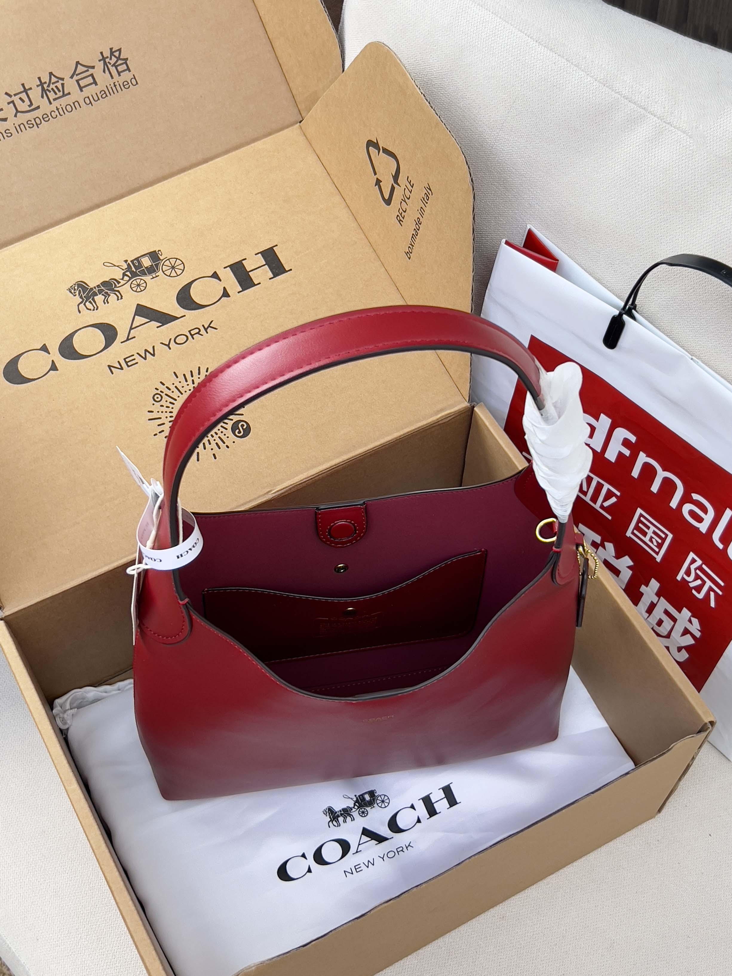 Red leather tote-style bag with top handles in gift packaging