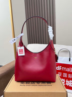 Red leather bucket-style bag with top handle, shown on gift box
