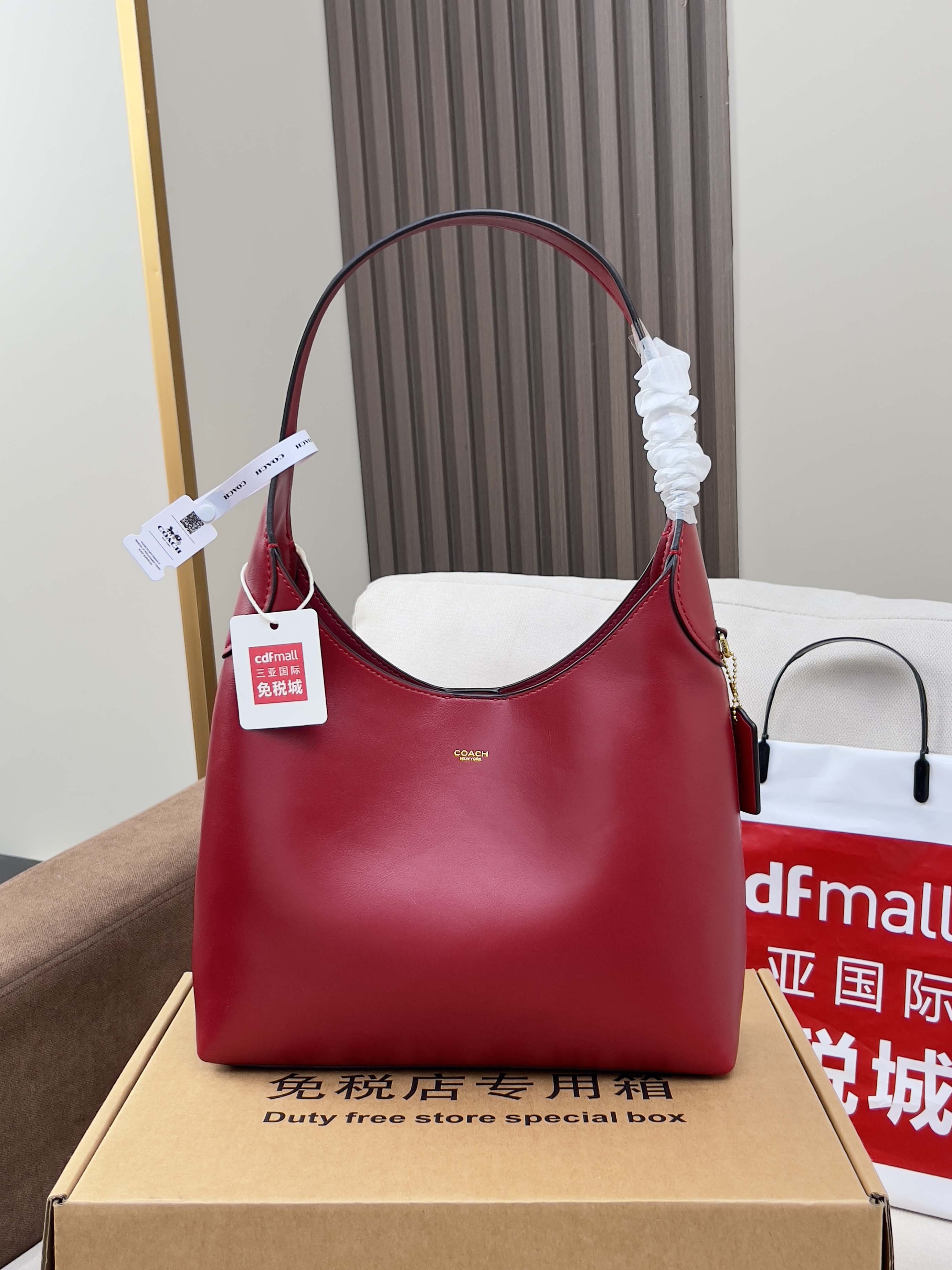 Red leather bucket-style bag with top handle, shown on gift box