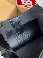 COACH navy leather bag close-up with embossed logo patch and stitched edge
