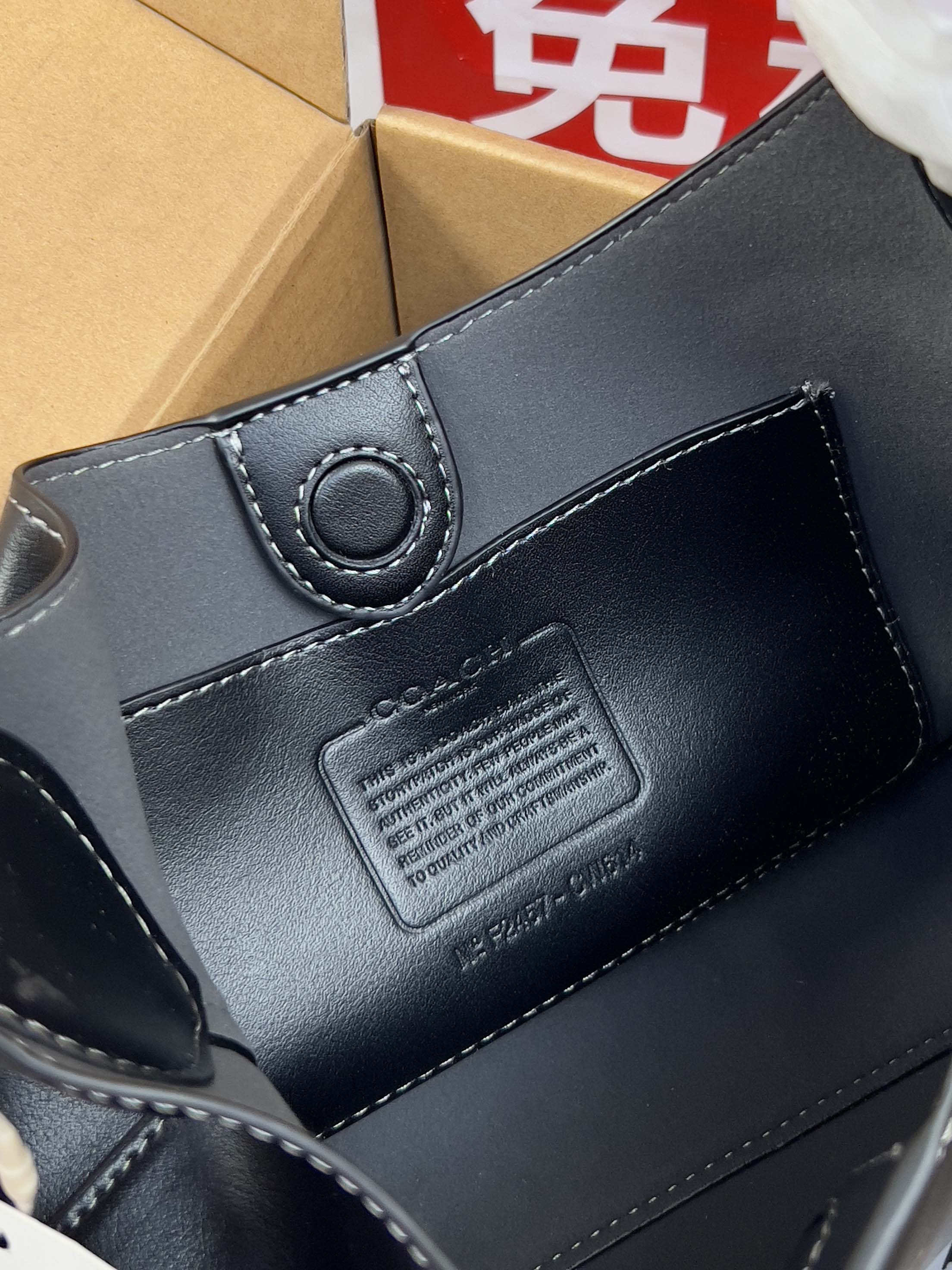 COACH navy leather bag close-up with embossed logo patch and stitched edge