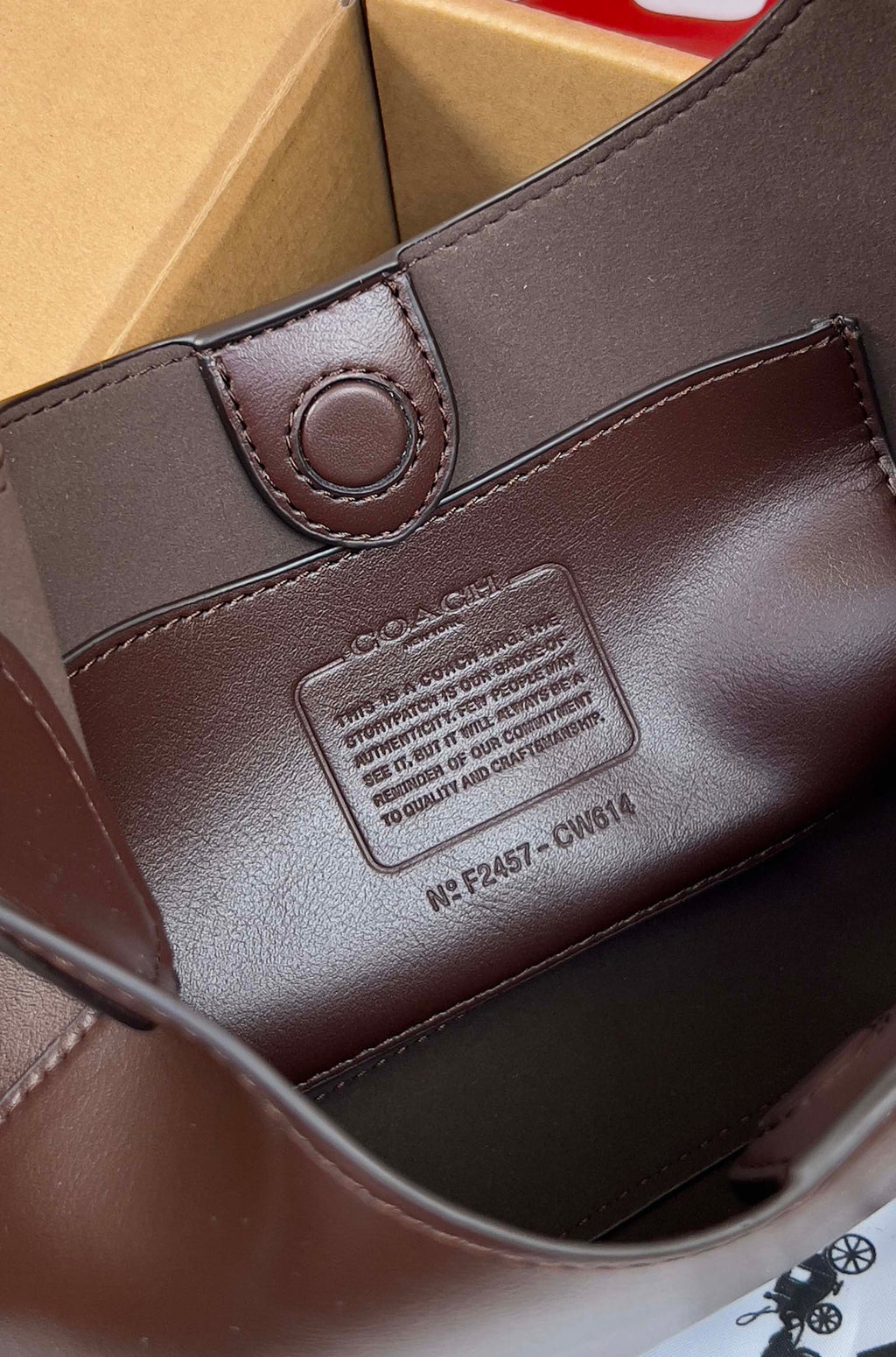 Coach dark brown leather bag close-up with brand patch and circular snap tab