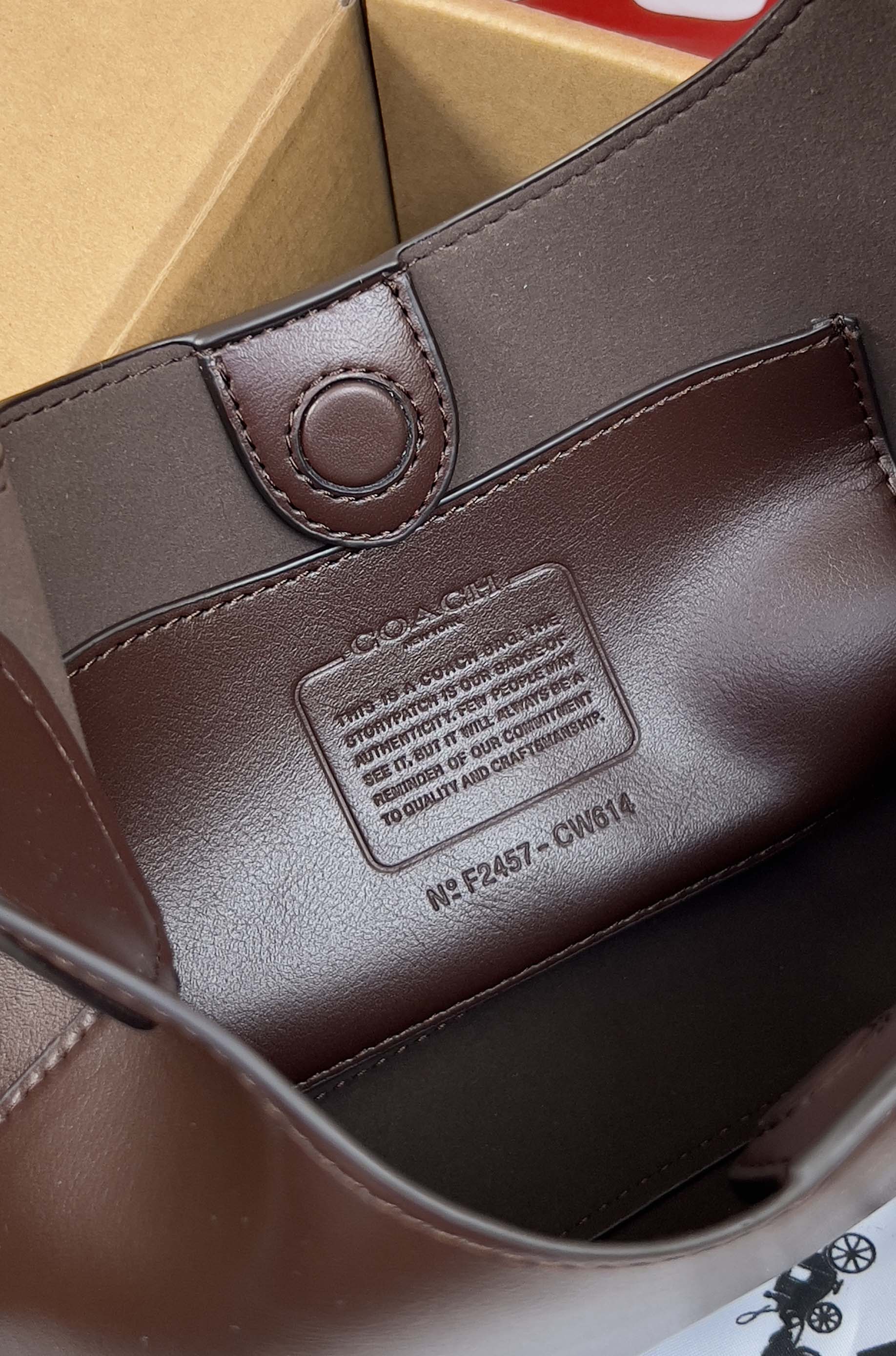 Coach dark brown leather bag close-up with brand patch and circular snap tab