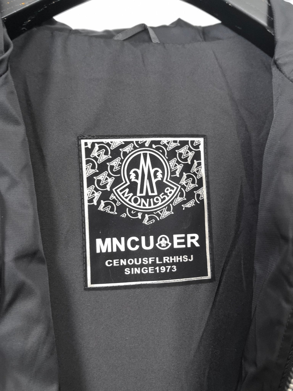 Black hooded jacket inner brand label patch on lining.