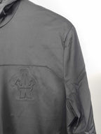 Black hooded jacket chest logo patch with curved seam detail.
