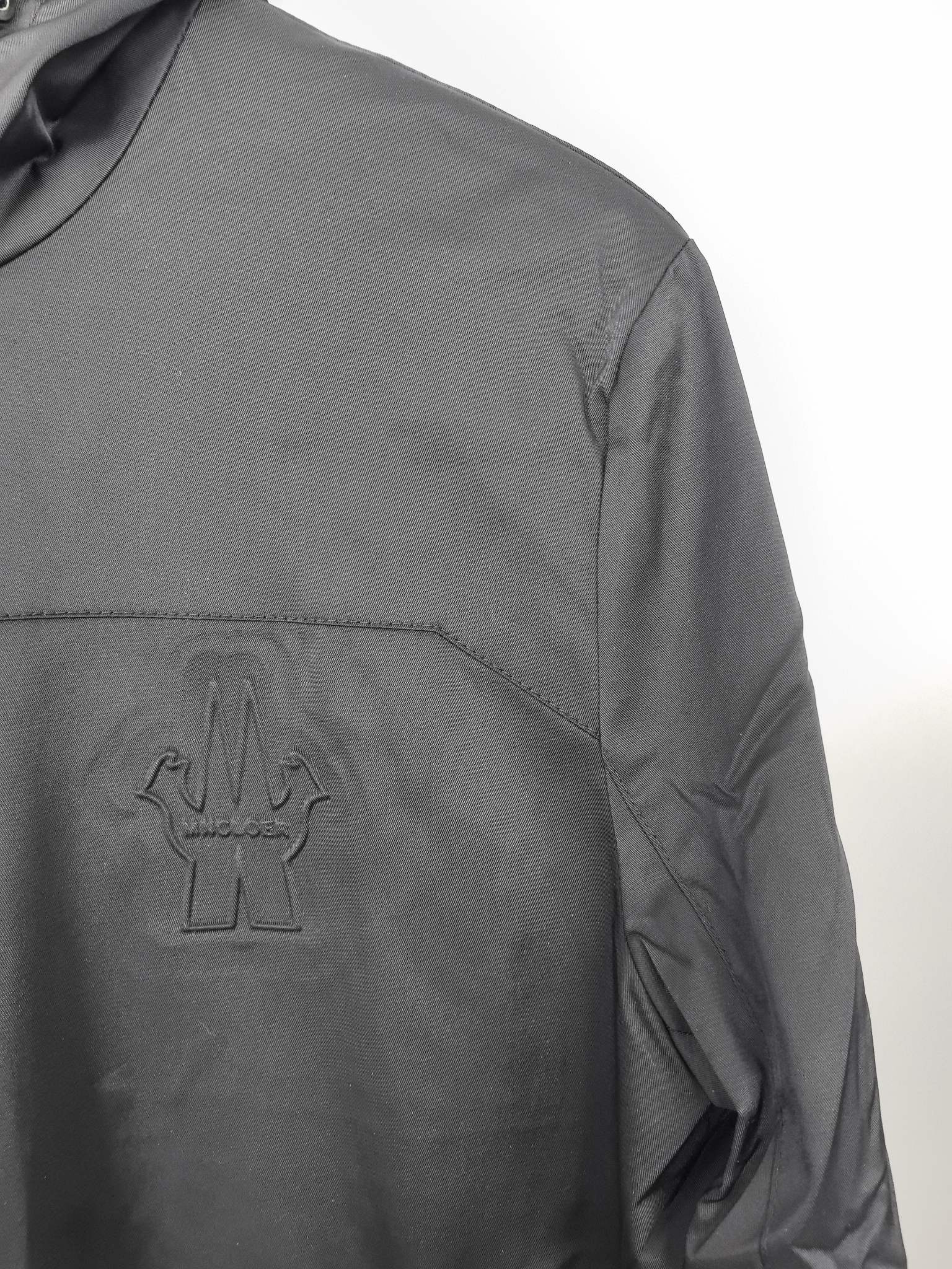 Black hooded jacket chest logo patch with curved seam detail.