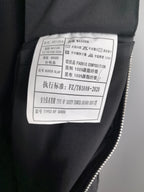 Black jacket care label with fabric composition and washing instructions.