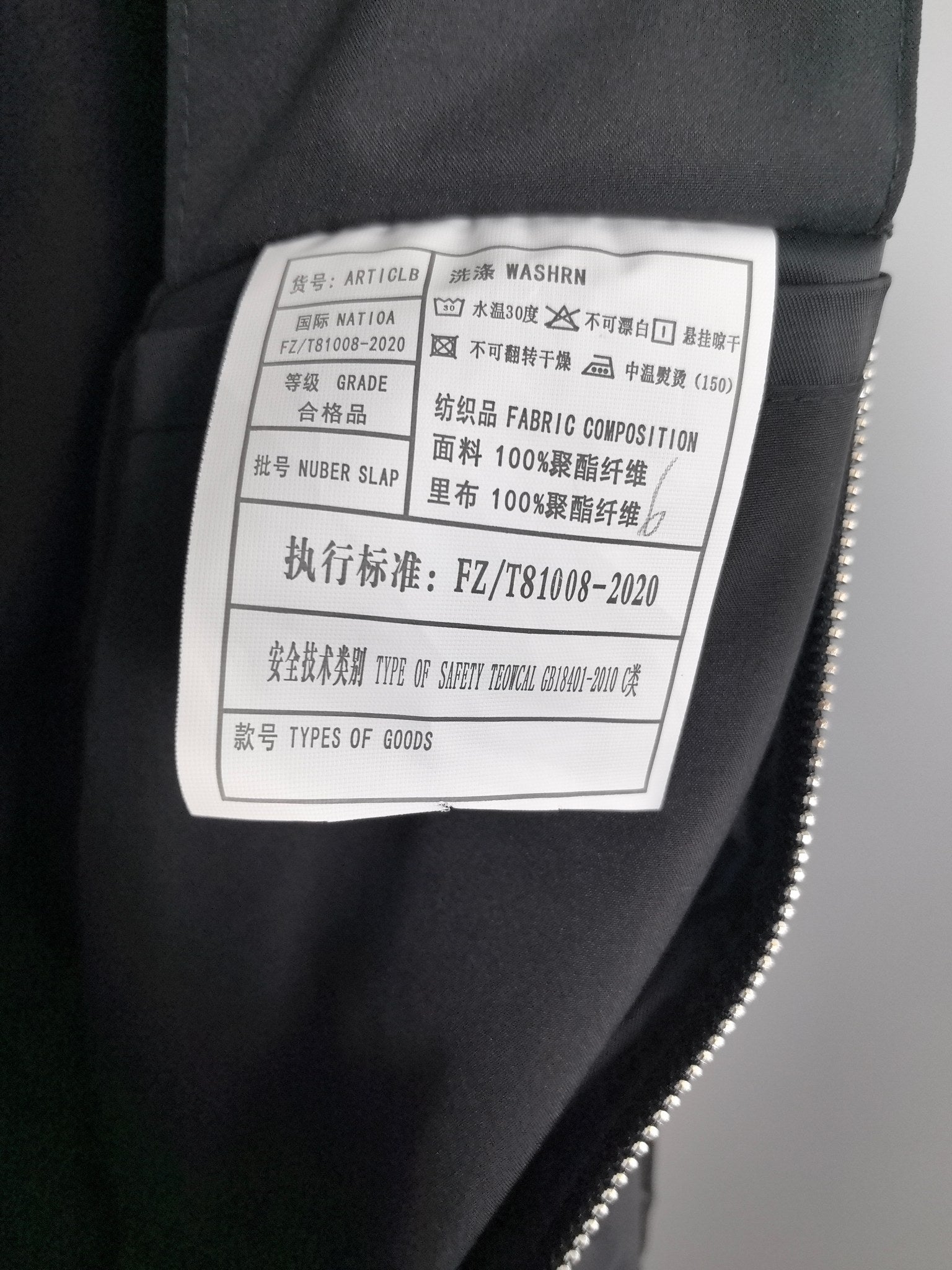 Black jacket care label with fabric composition and washing instructions.