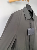 Prada zip-up jacket side view with dark gray fabric, front zipper, and tag