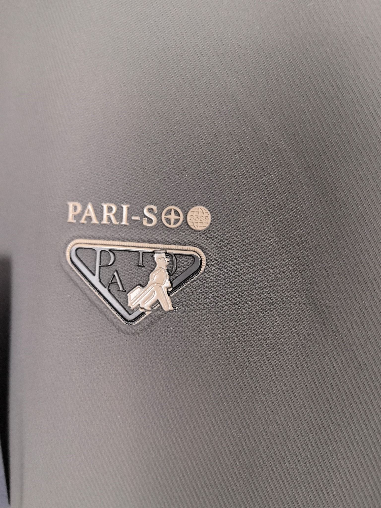 Prada jacket fabric close-up with PARI-SO logo and triangular emblem