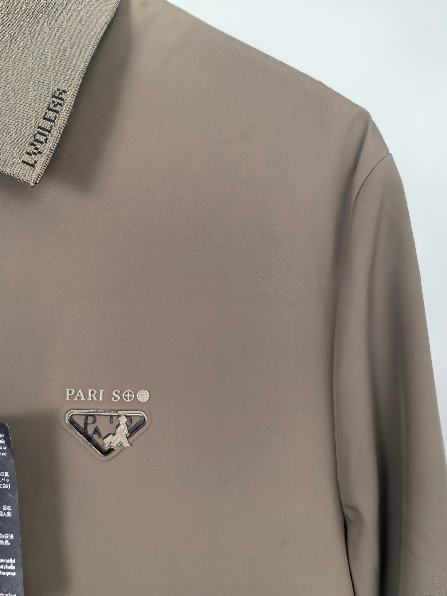 Men's Prada jacket chest close-up in taupe with logo patch and zip edge