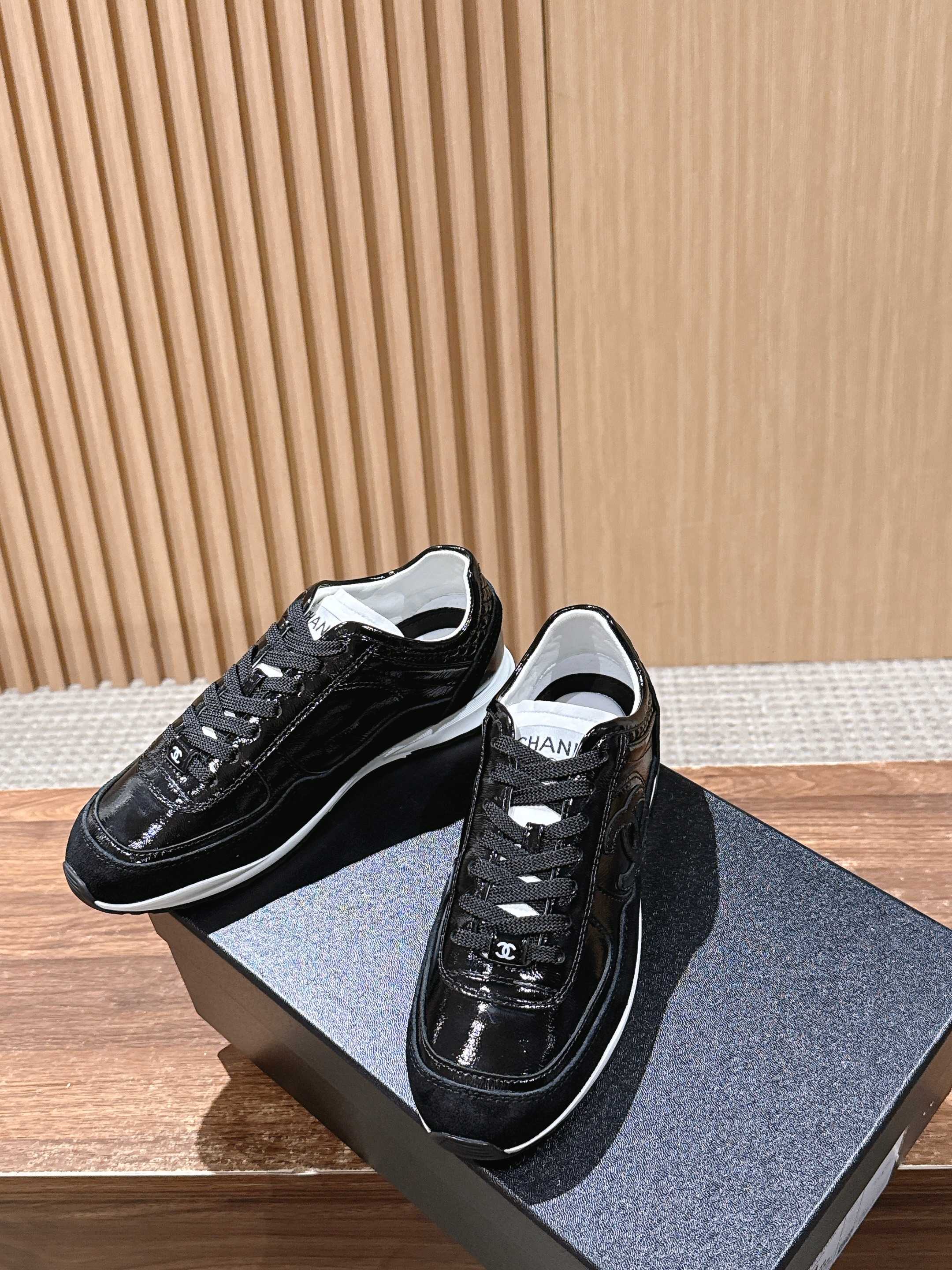 Black lace-up sneakers with white sole, on gray shoebox, Chanel branding
