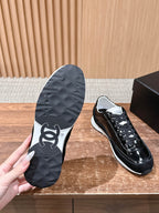 Black shoe outsole with Chanel-like logo, paired with white-trimmed sneakers