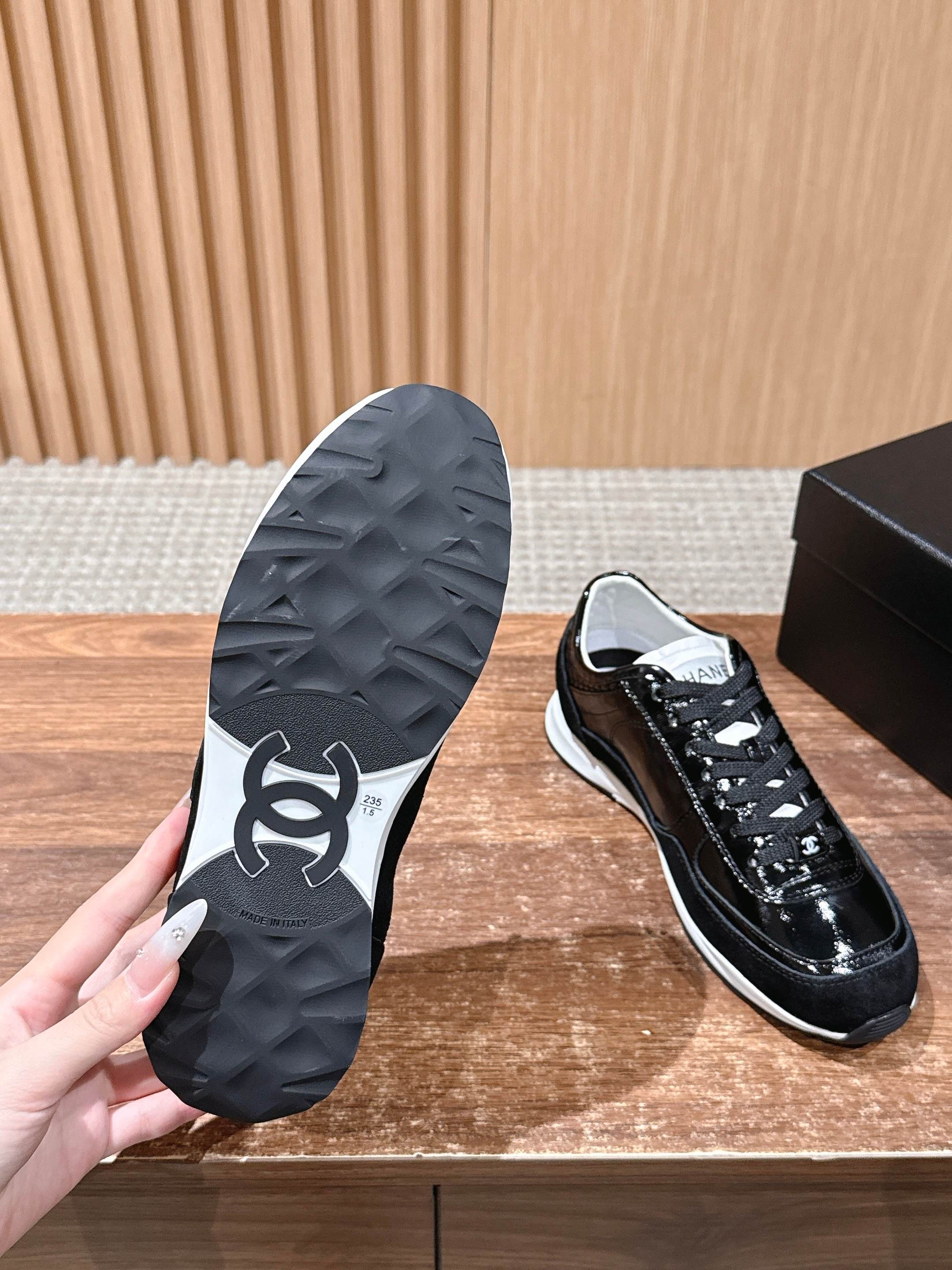 Black shoe outsole with Chanel-like logo, paired with white-trimmed sneakers