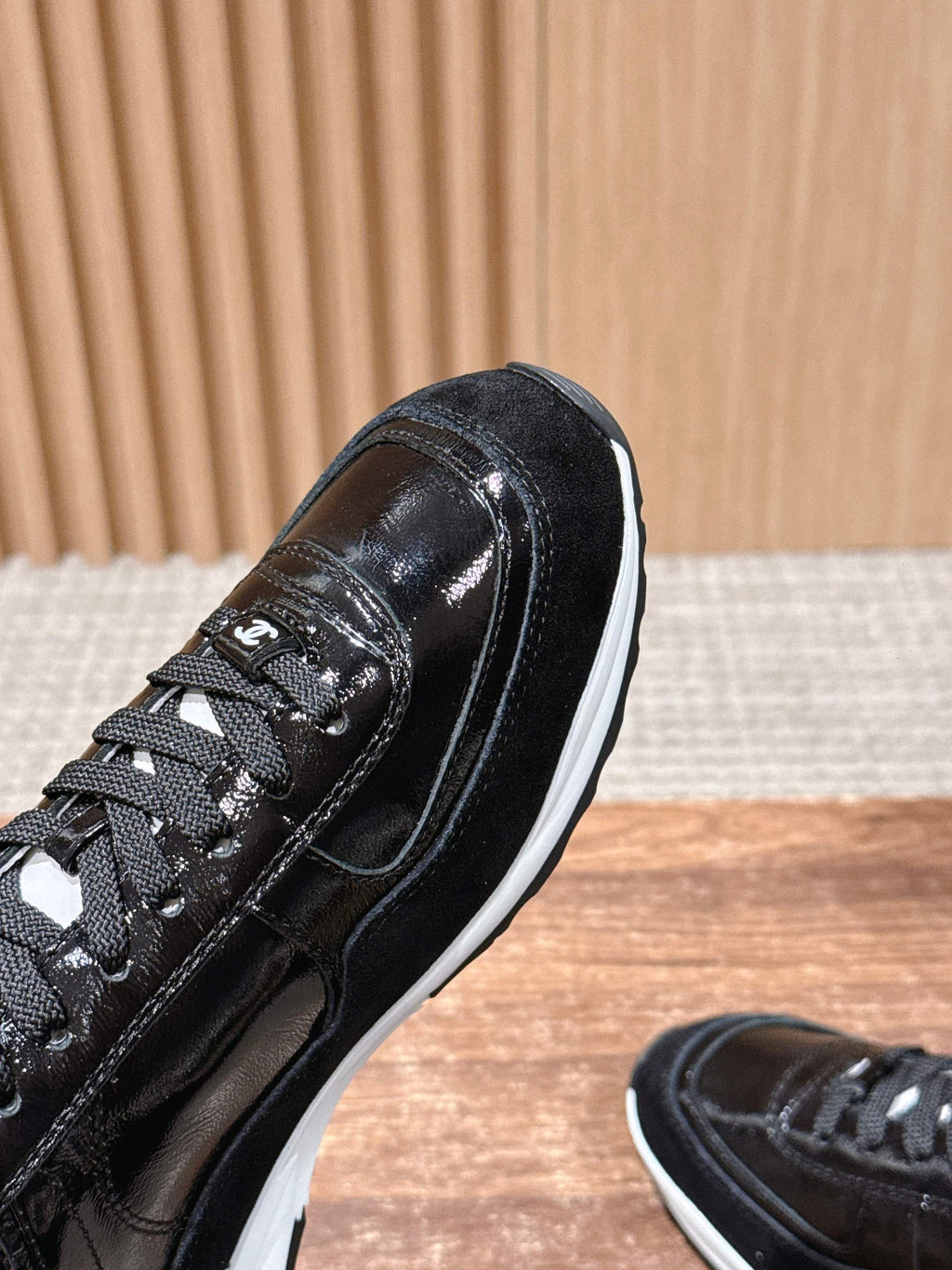 Black lace-up sneaker close-up with glossy finish and white midsole