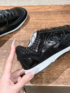 Black lace-up sneaker with decorative swirl stitching and white sole