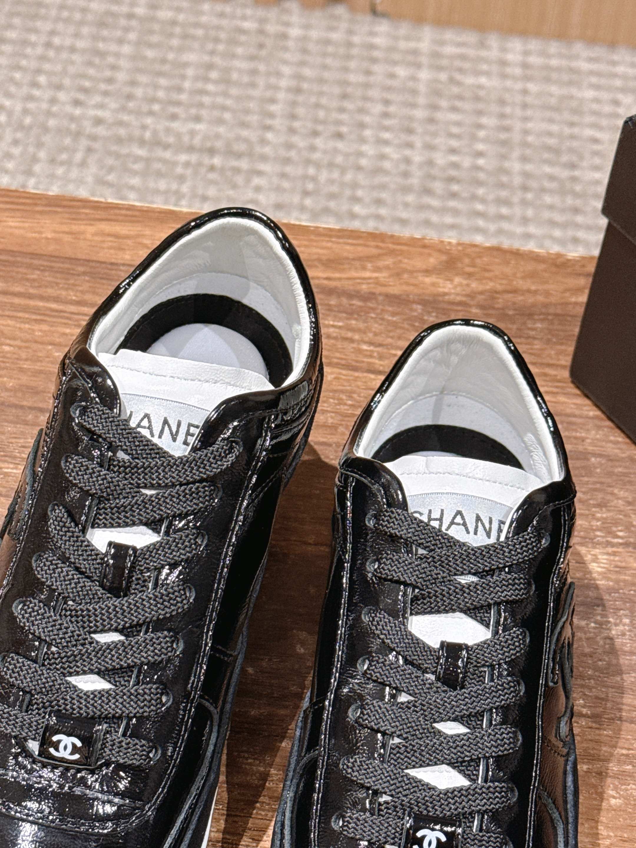 Black lace-up sneakers with white lining and Chanel logo on tongue