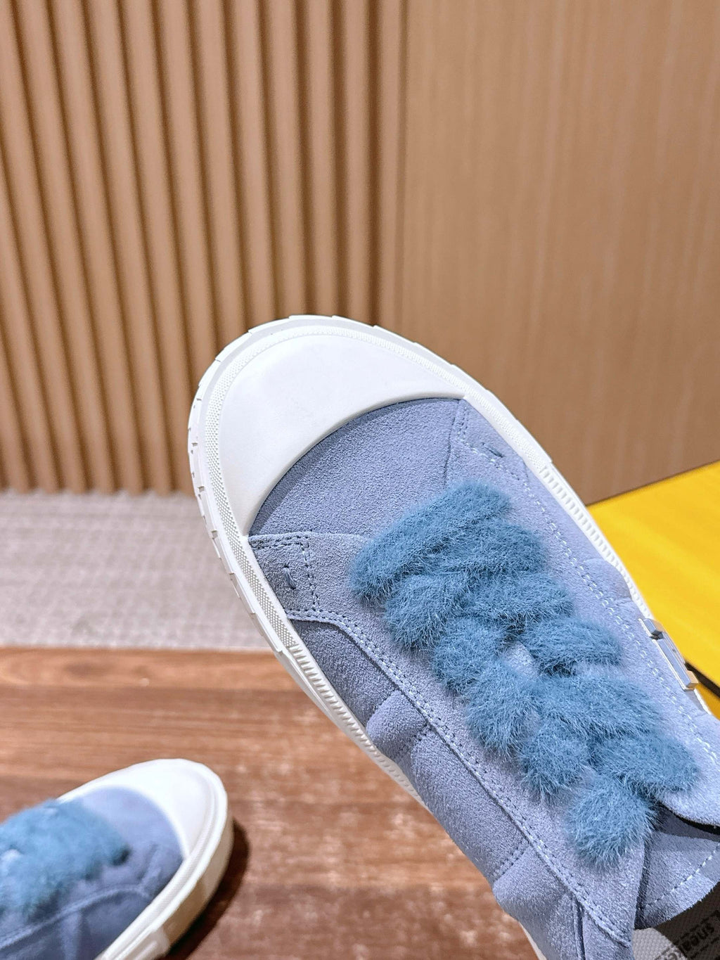 Light blue suede slip-on sneaker with blue fuzzy strap detail and white edge trim