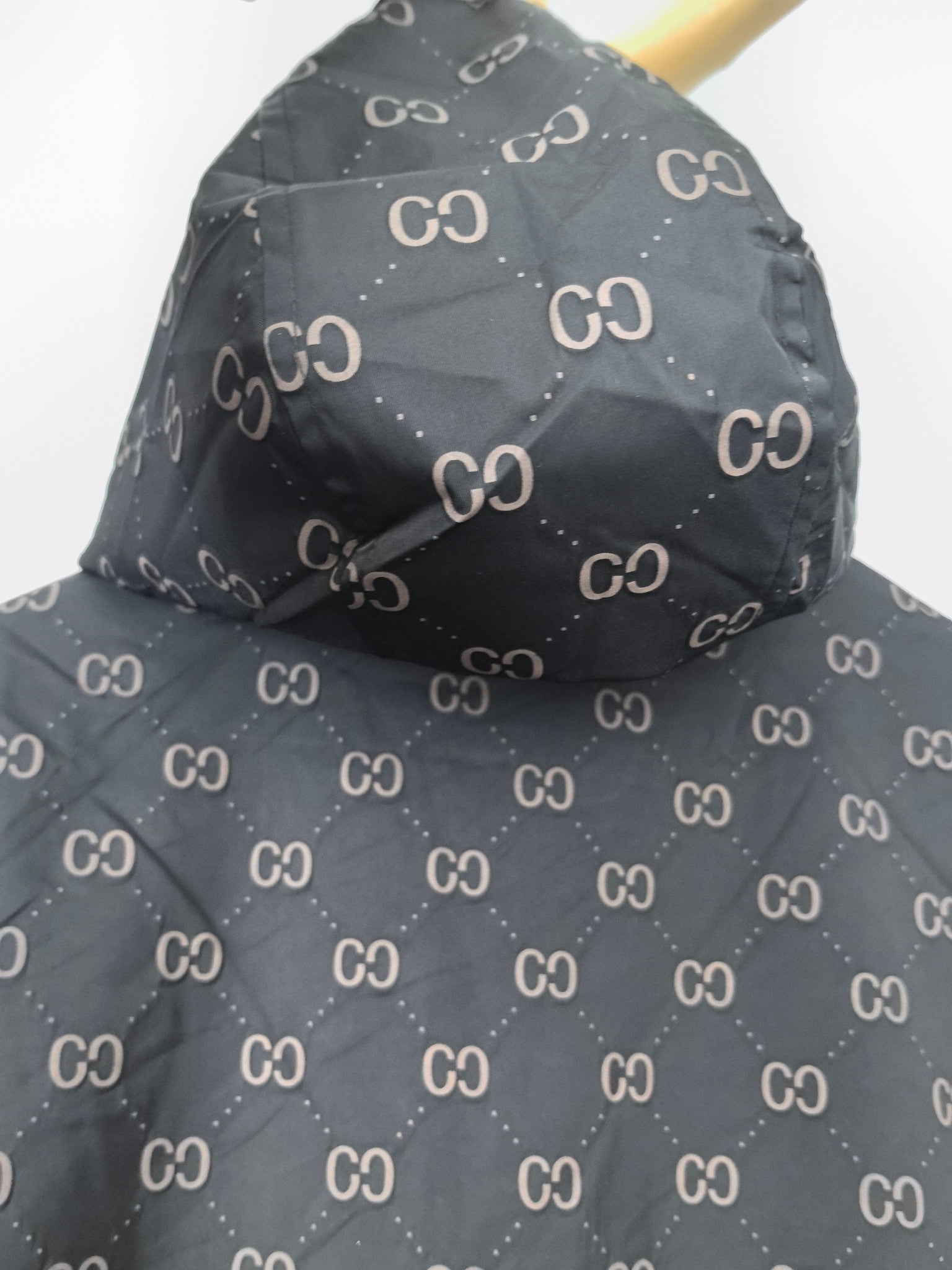 Gucci hooded jacket, dark gray with repeating GG pattern, draped shoulder view