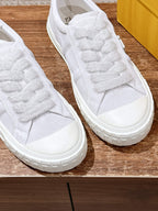Close-up of white Fendi unisex sneakers, lace detailing and thick rubber sole
