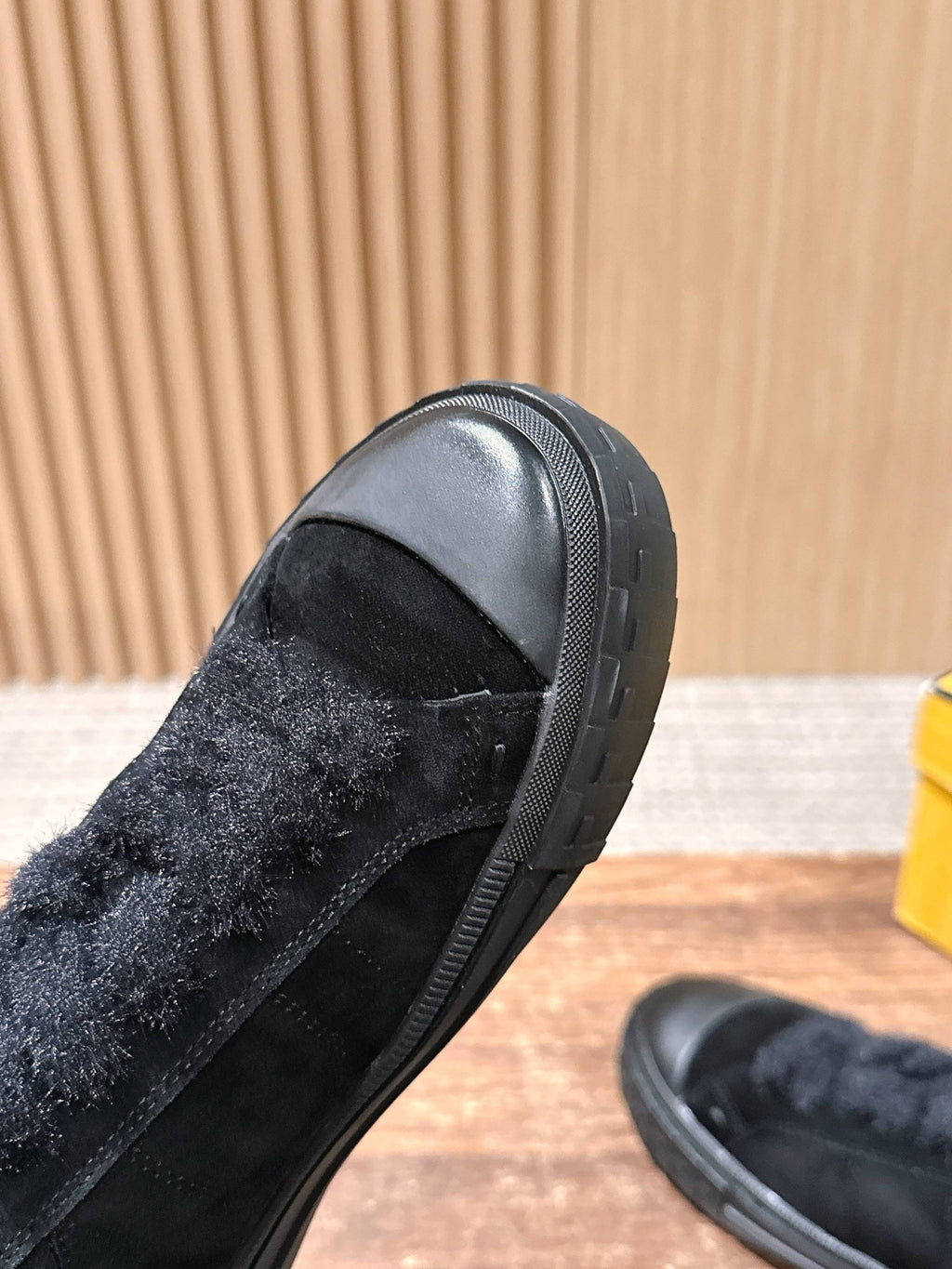 Black suede slip-on shoe heel close-up with textured rubber sole edge