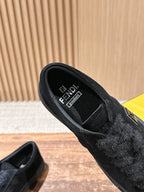 Black suede slip-on shoes showing interior lining and branding on the insole