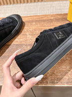 Black suede slip-on shoe with embossed logo on side and cushioned rubber sole