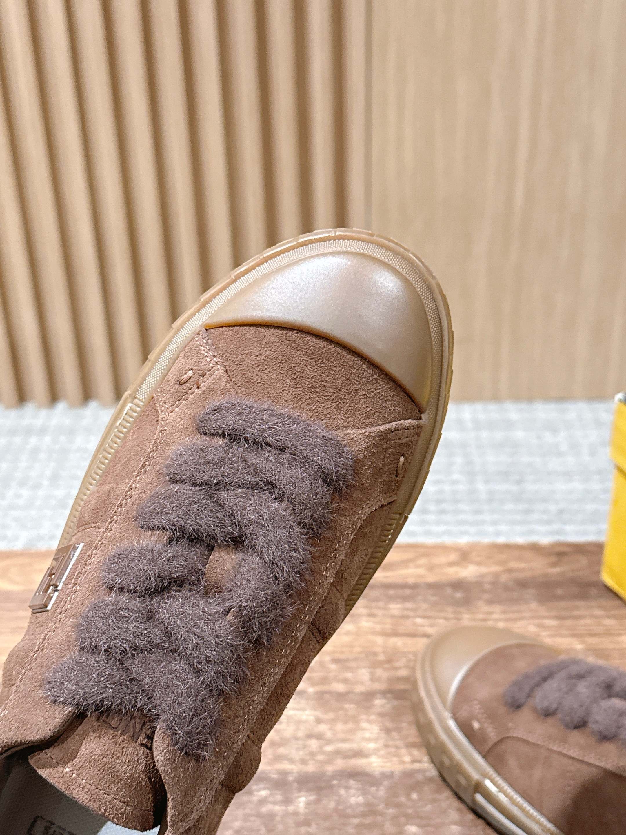 Brown suede sneaker with fuzzy lace panel and rounded toe, close-up