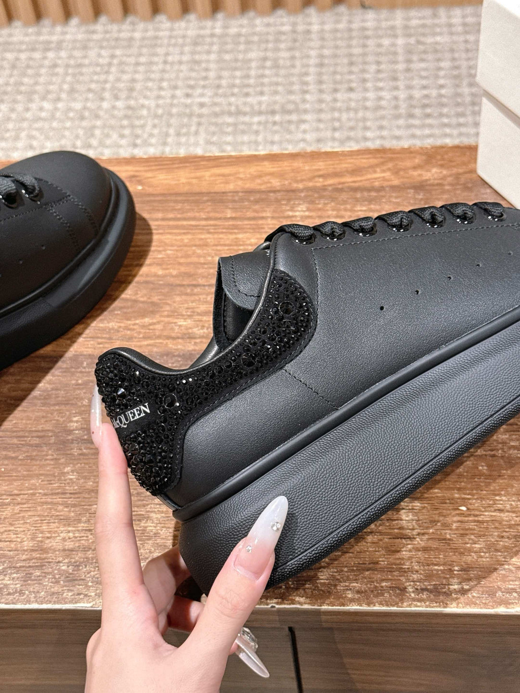 Black leather sneaker close-up with textured side panel and lace-up detail