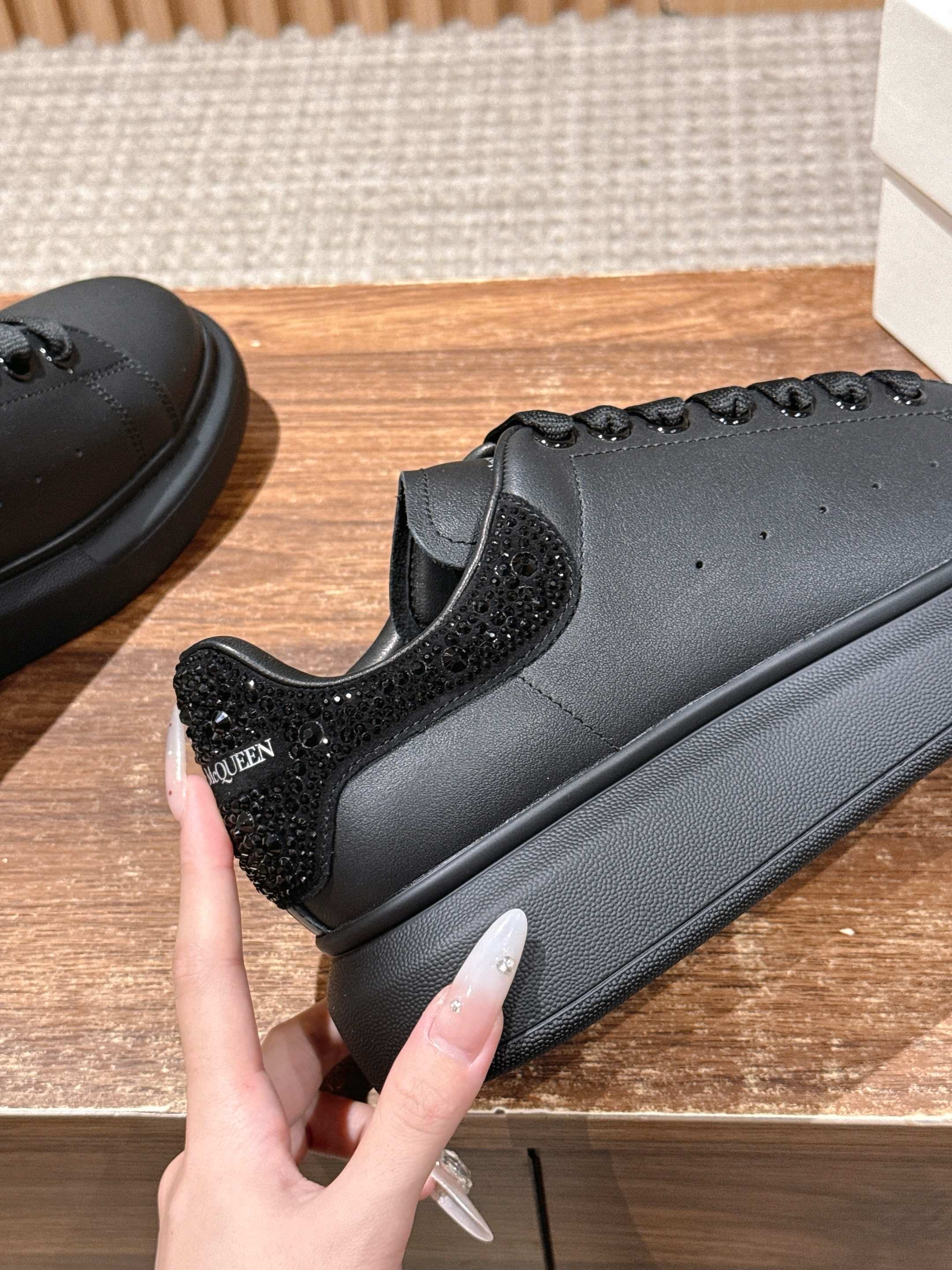 Black leather sneaker close-up with textured side panel and lace-up detail